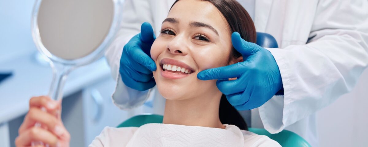A person smiling as a dentist points their mouth