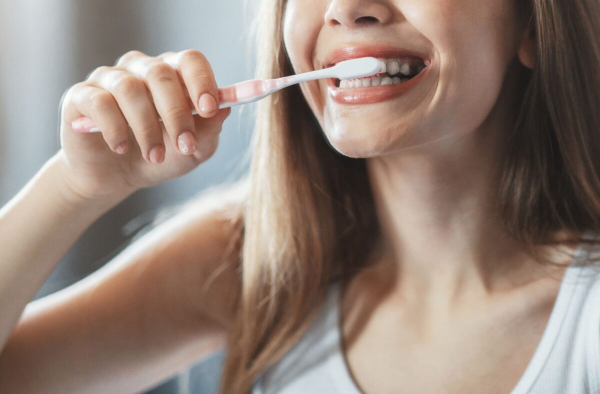 A person manually brushing their teeth at home
