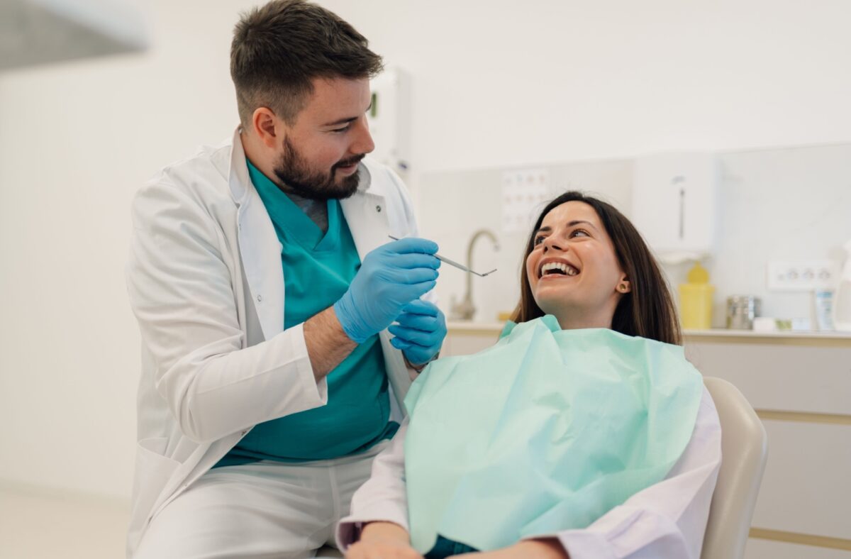 A patient talking to a dentist and smiling before getting their dental exam done.