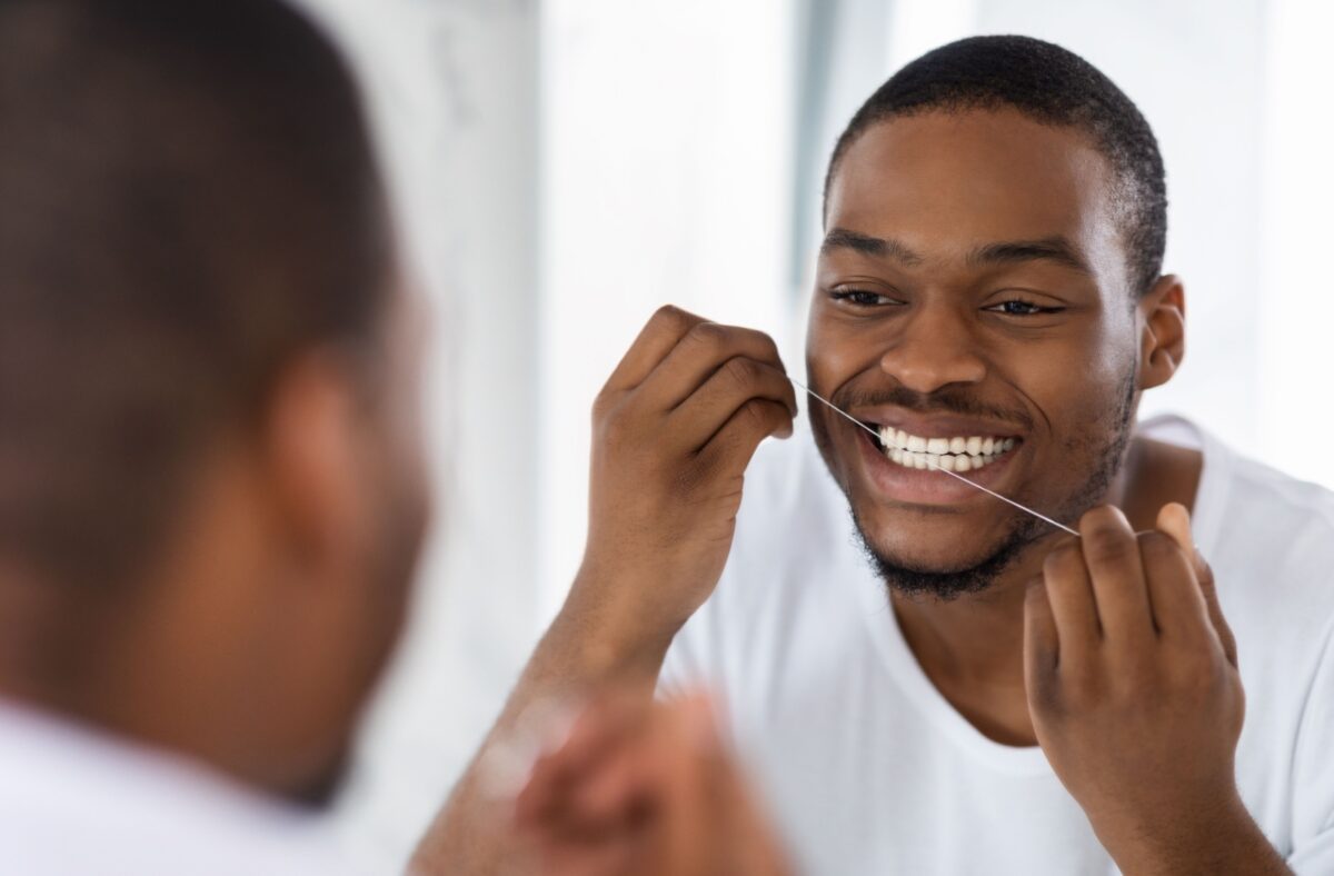 A person looking in the mirror as they floss their teeth