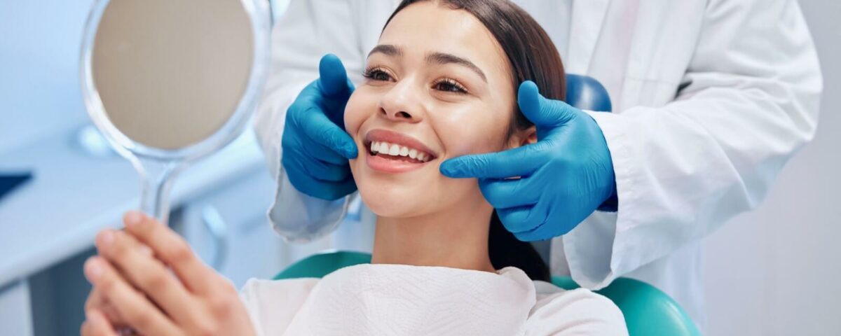 A person smiling while looking in the mirror at the dentist