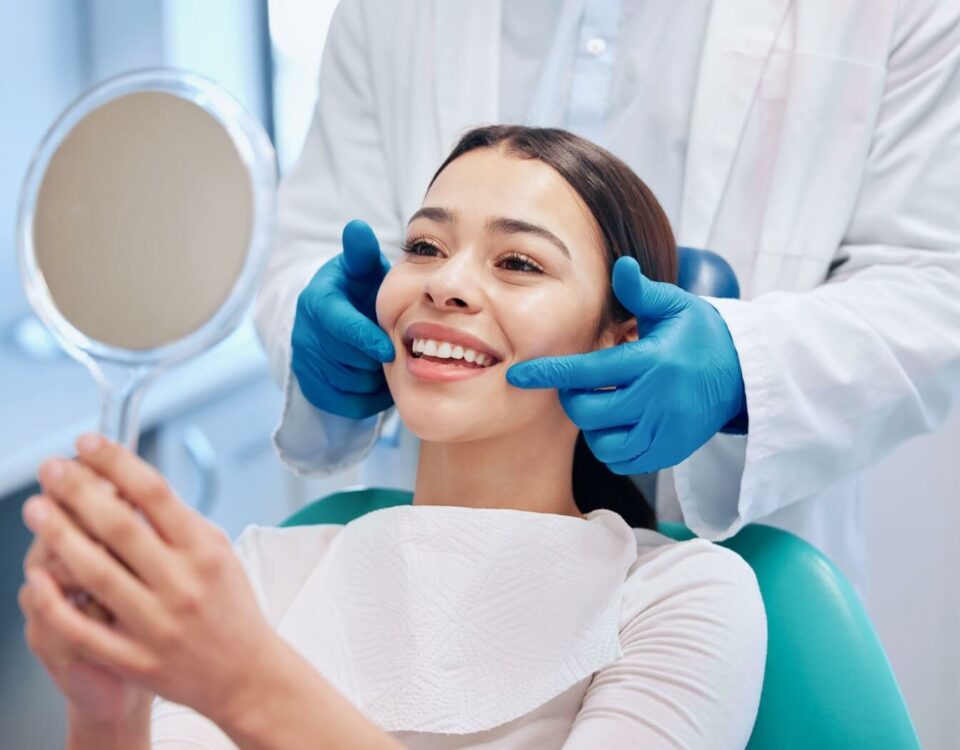 A person smiling while looking in the mirror at the dentist